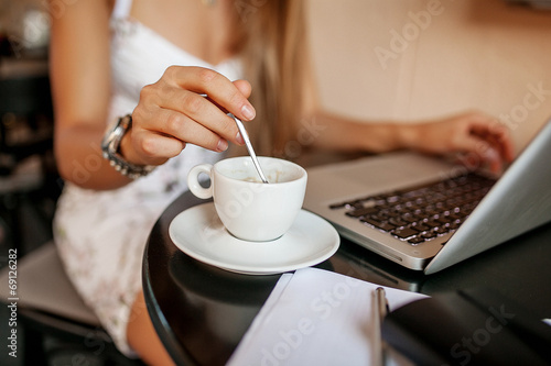 Young business woman in cafe drinking coffee with laptop