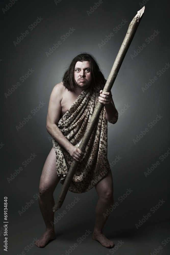 Dangerous wild man in skin of beast threaten with big stick. Dangerous wild man in skin of beast threaten with big stick.
