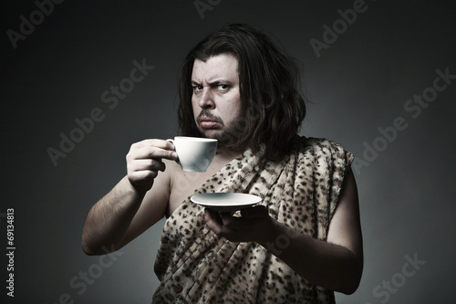 Savage man in skin of beast drink tea or coffee