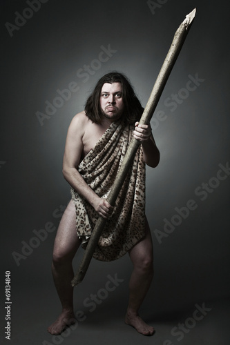 Dangerous wild man in skin of beast threaten with big stick.