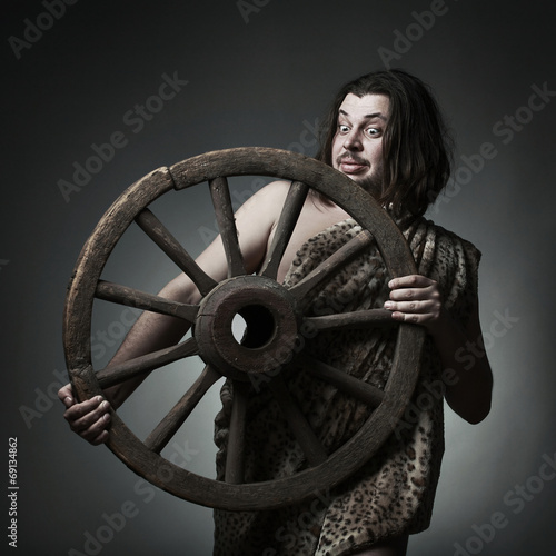 Caveman wearing leopard skin hold old wooden wheel.