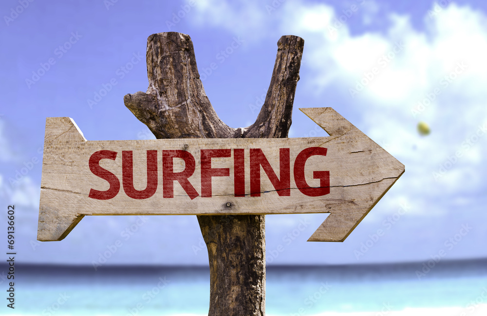 Surfing wooden sign with a beach on background