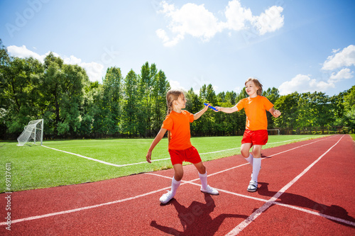 Running girl with baton hands it to other runner