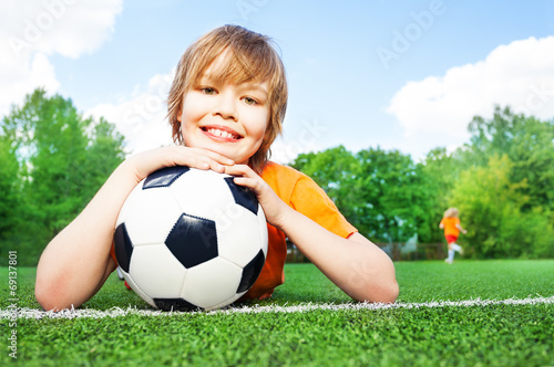 Boy holds football with bending in elbows arms
