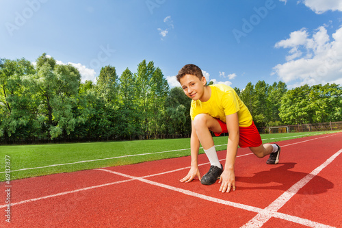 Boy in ready position on one bend knee to run
