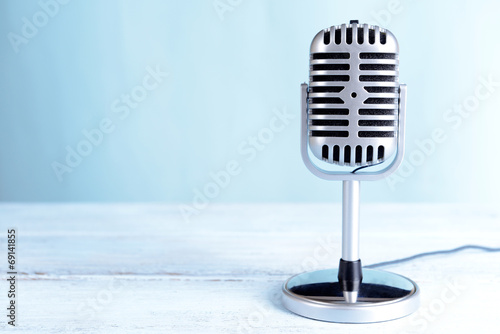 Vintage microphone on table on light blue background