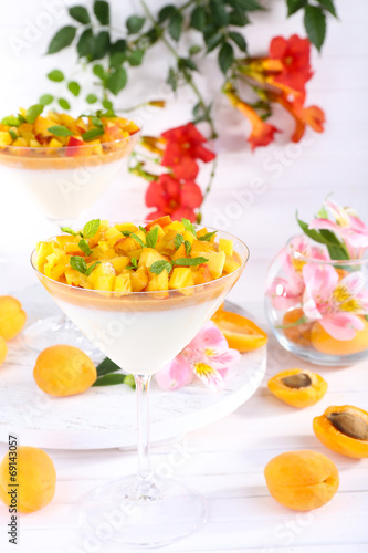 Apricot dessert in glasses on table on bright background