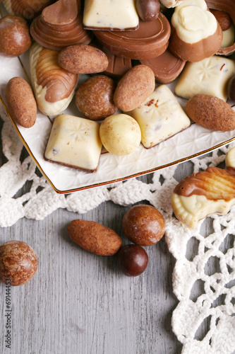 Different kinds of chocolates on plate on wooden table