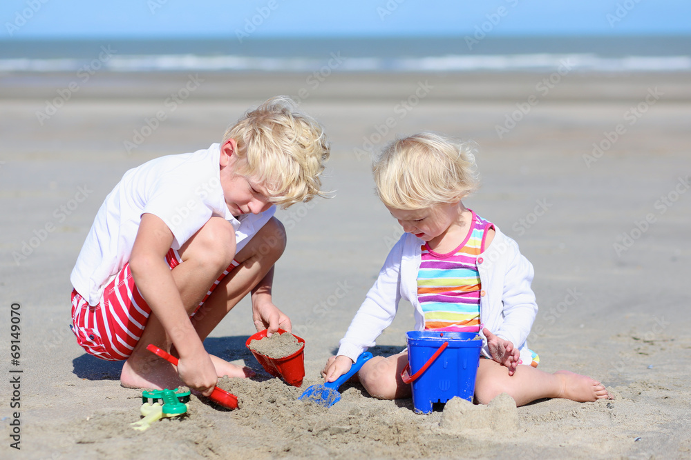Brother and sister building sand castles on the beach Brother and sister building sand castles on the beach