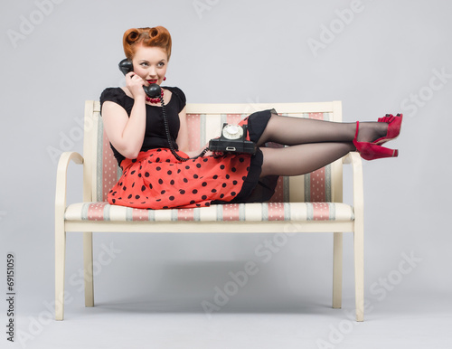 Woman talking on retro phone lying on a sofa. photo