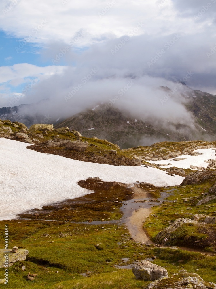 Thin footpath in snowy autumn meadows of high Alpine mountains