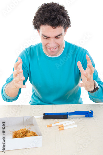 angry man making cigarettes with device for cigar and dry tobacc photo