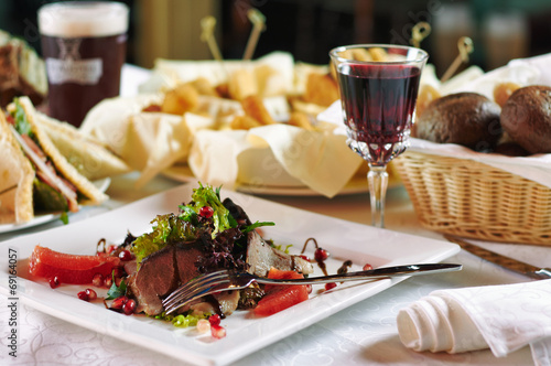 Meat salad on plate and glass of wine