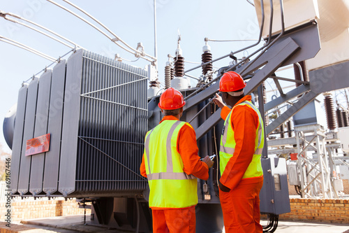 Naklejka electricians standing next to a transformer