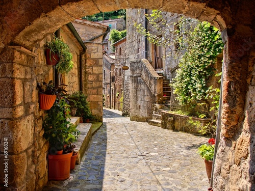 Arched cobblestone street in a Tuscan village, Italy