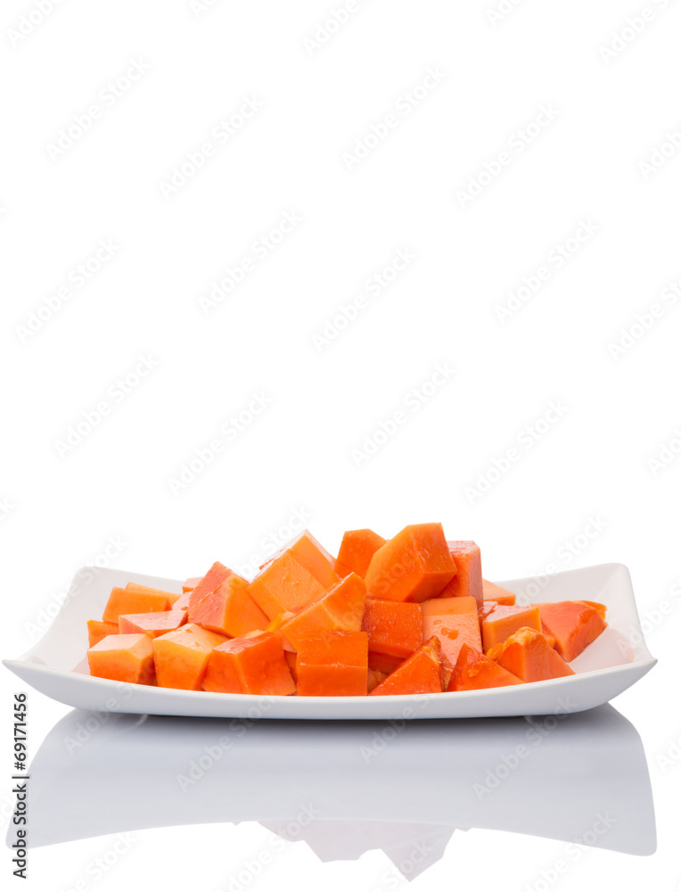 Bite sized papaya fruit on white plate over white background Bite sized papaya fruit on white plate over white background