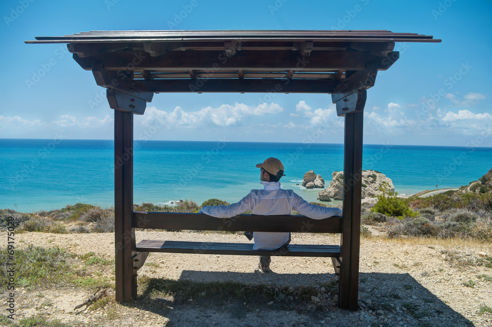man sitting under roof  looking at sea