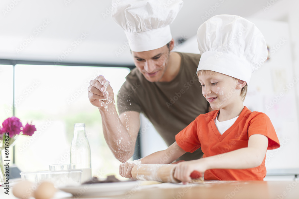 a father and his son preparing a cake in the kitchen