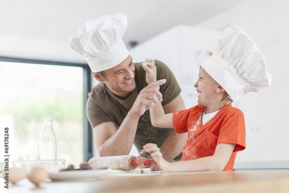a father and his son preparing a cake in the kitchen