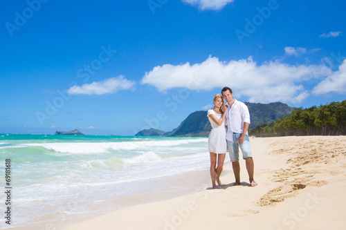 Cheerful couple embracing and posing on the beach on a sunny day