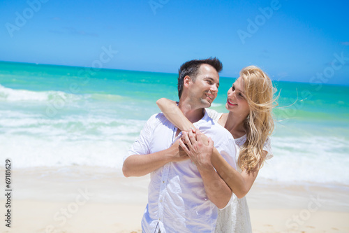 Cheerful couple embracing and posing on the beach on a sunny day © RightFramePhotoVideo
