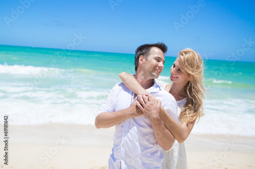 Cheerful couple embracing and posing on the beach on a sunny day