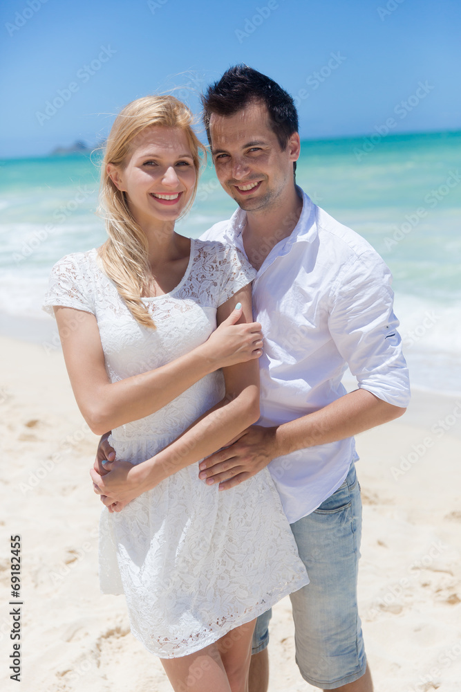 Cheerful couple embracing and posing on the beach on a sunny day