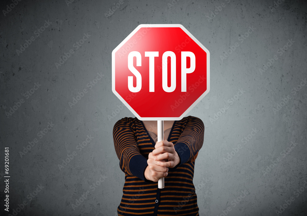 Young woman holding a stop sign - obrazy, fototapety, plakaty 