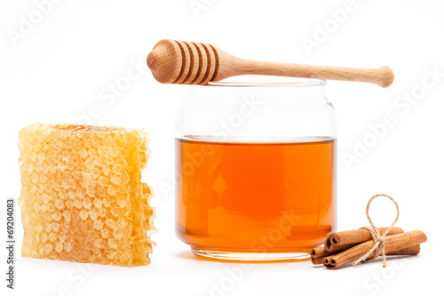 Honey in jar with dipper, honeycomb, cinnamon on isolated backgr photo