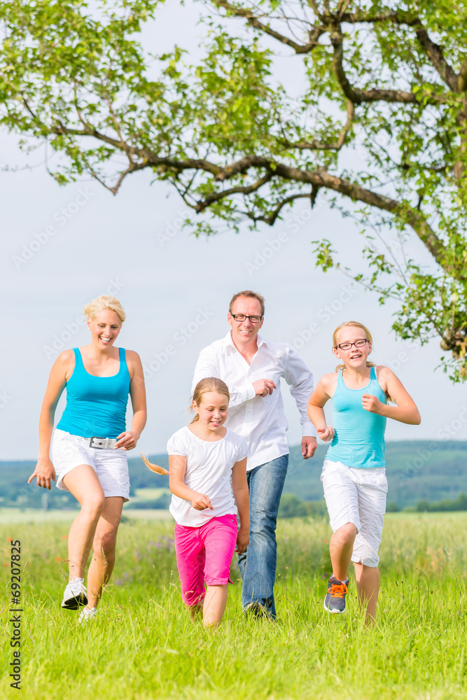 Familie rennt über Feld oder Wiese im Sommer Familie rennt über Feld oder Wiese im Sommer