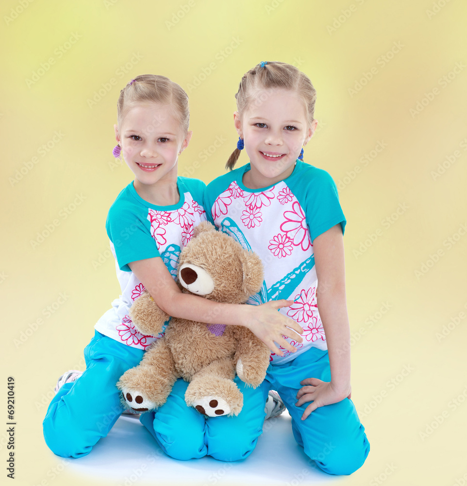Twin sisters hugging her favorite teddy bear. Twin sisters hugging her favorite teddy bear.