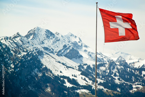  Flag of Switzerland on the Alps mountains landscape background.