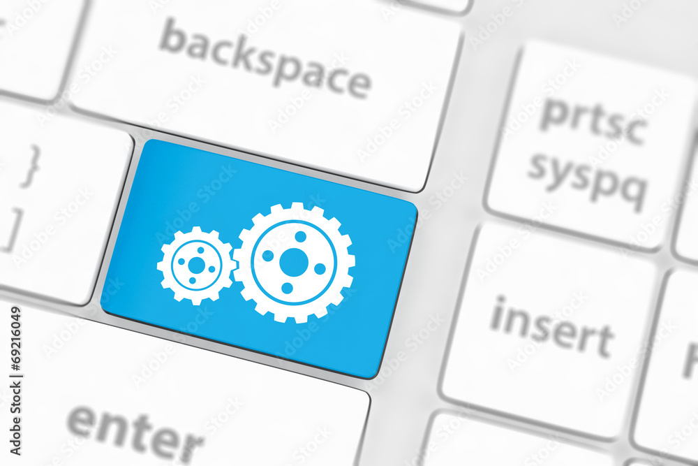 cogwheel gear mechanism on button on white computer keyboard. cogwheel gear mechanism on button on white computer keyboard.