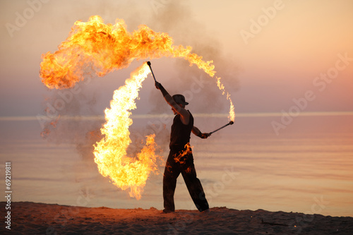 Fotografia Professional fire juggler performing on the beach