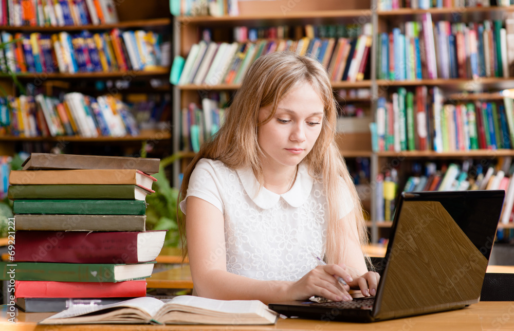 pretty female student typing on notebook in library pretty female student typing on notebook in library