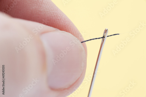 Person threading a needle with yarn
