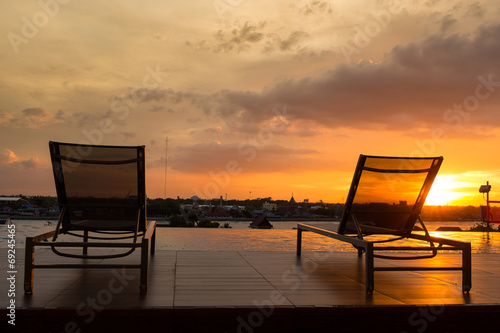 Swimming pool chair by swimming pool with sunset