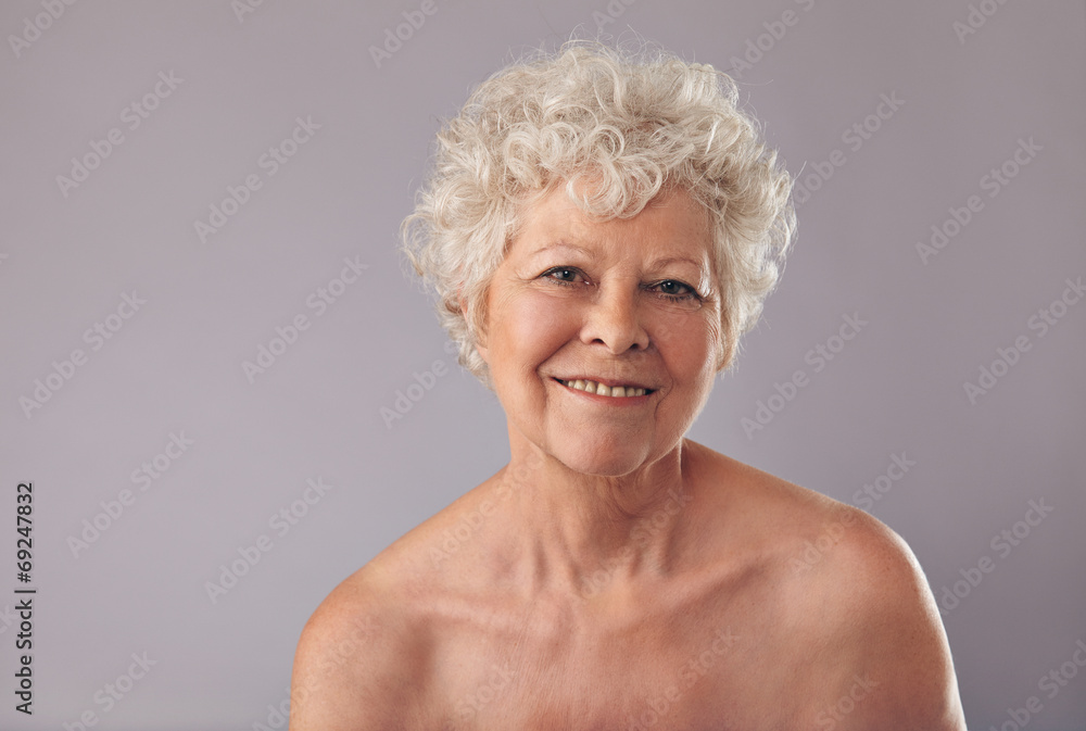 Senior woman smiling on grey background Senior woman smiling on grey background