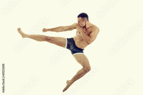 Young muscular boxer fighter doing exercise with a perfect kick