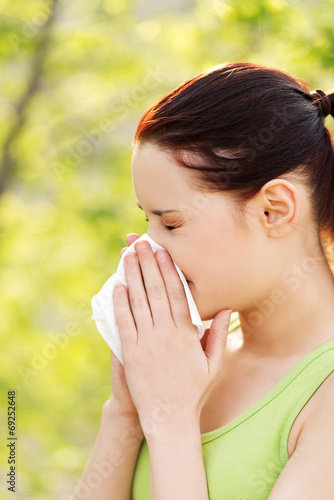 Attractive young woman outdoor with tissue.