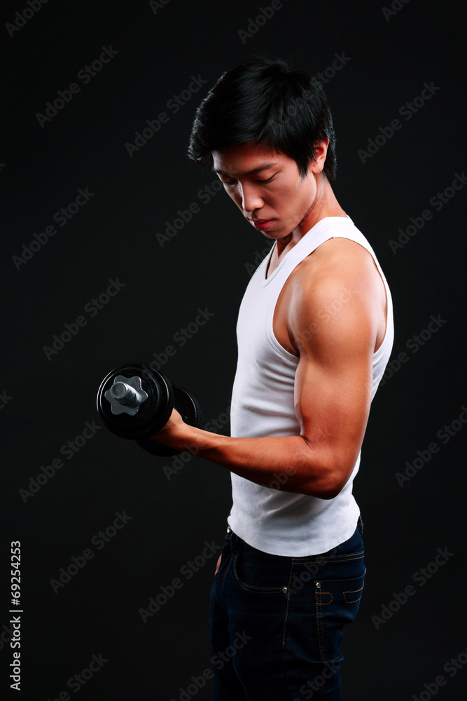 Asian man working out with dumbbells on black background Asian man working out with dumbbells on black background