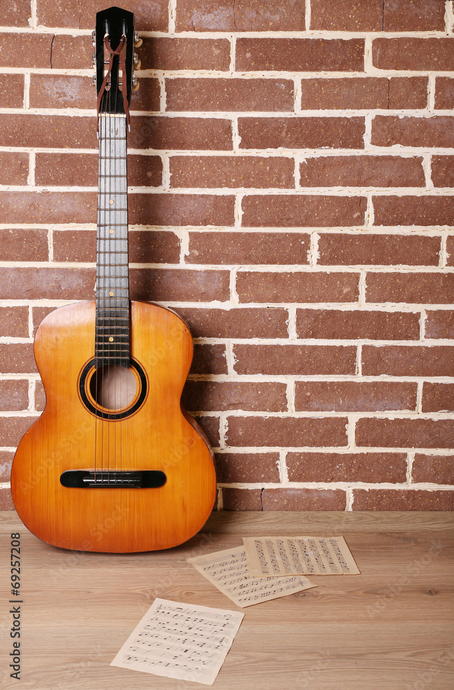 Guitar on the floor on brick wall background