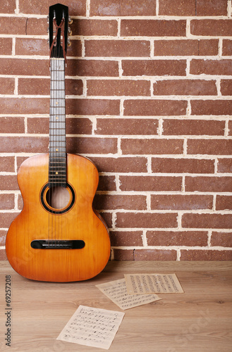 Guitar on the floor on brick wall background © Africa Studio