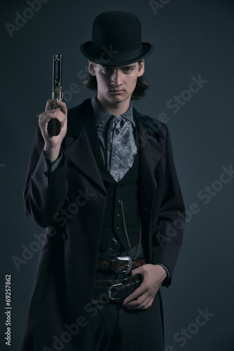 Western 1900 fashion man with brown hair and hat holding gun. St