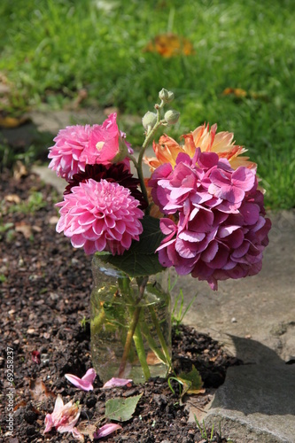 Sommerblumen im Wasserglas auf Friedhof