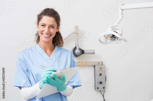 Dentist in blue scrubs writing on clipboard