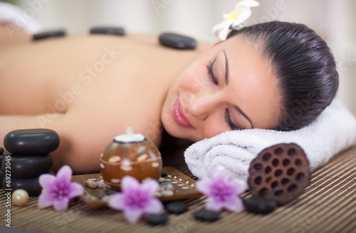 beautiful woman in spa salon with hot stones in back