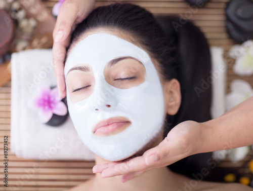  Spa therapy for young woman having facial mask at beauty salon
