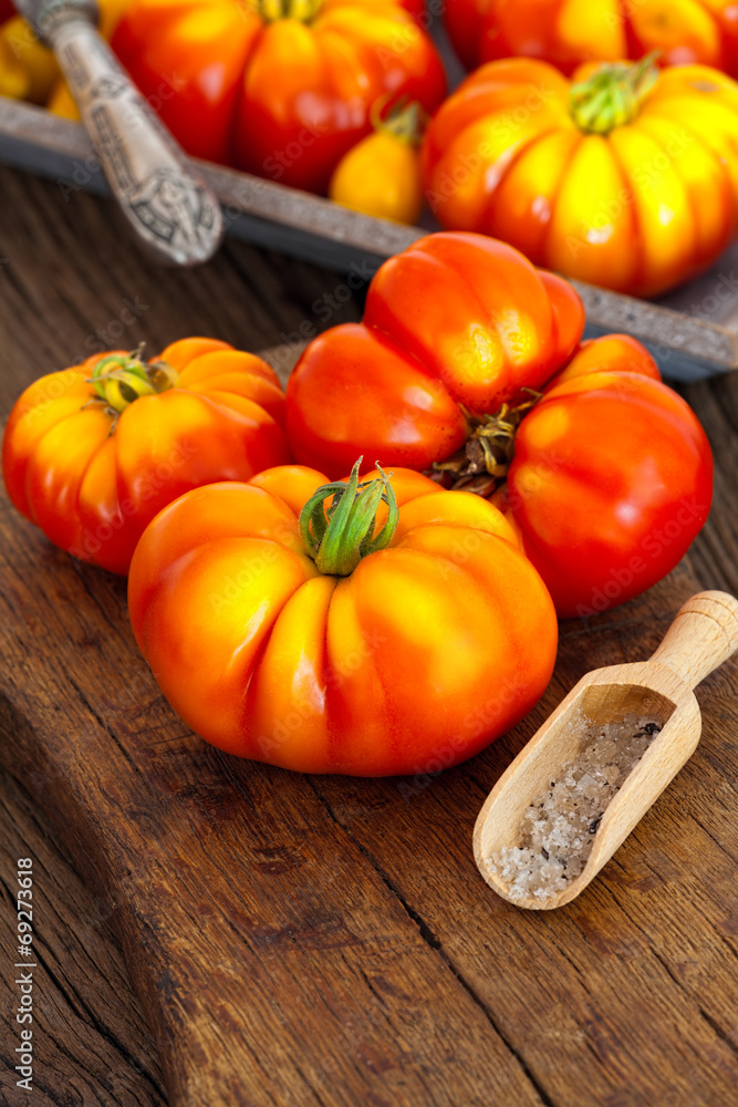 Reife Fleischtomaten mit Salz auf Holzbrett Reife Fleischtomaten mit Salz auf Holzbrett