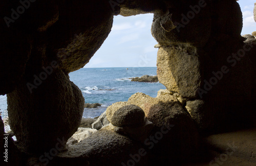 Costa brava beach view through a cave hole